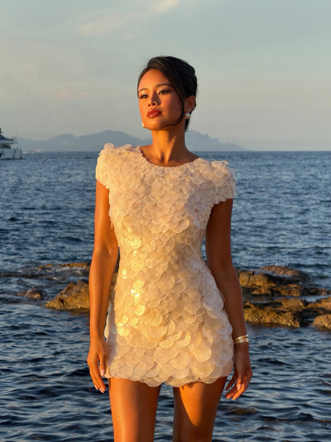Pat Chaveesak (Jarinpat), Paris-based fashion creator, in a white sequinned dress at sunset by the Mediterranean
